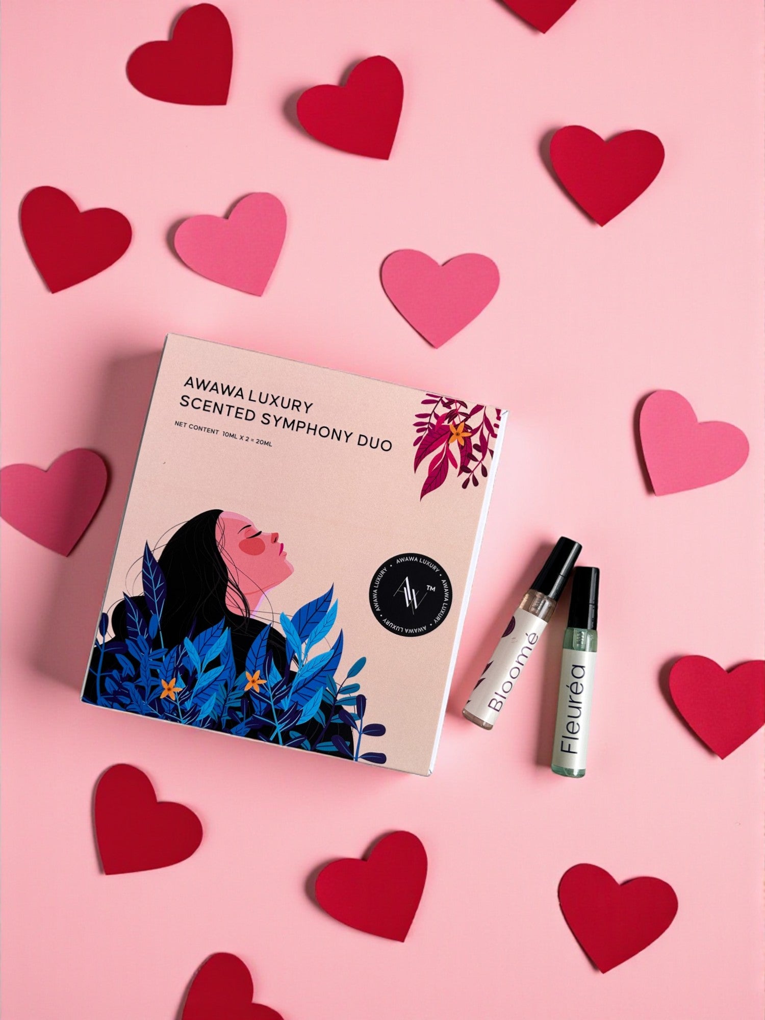“Scented Symphony Duo gift box with Bloomé and Fleuréa 10ml minis on a pink background with paper hearts”